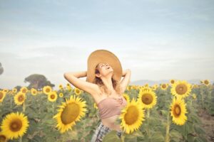 A woman in a sunflower field, embracing nature with joy under the summer sun.